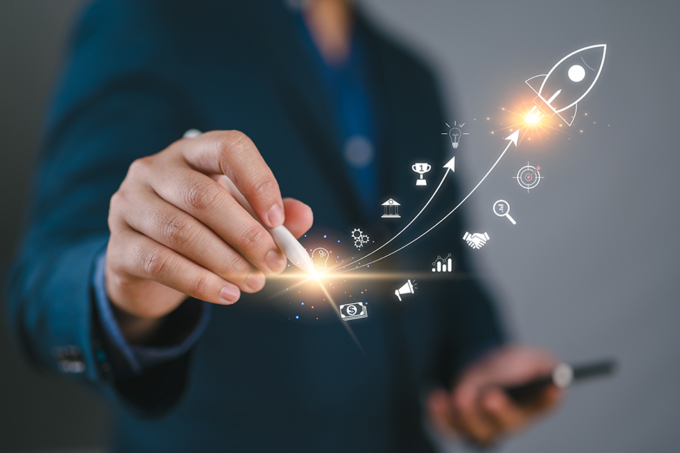 Geschäftsperson zeichnet mit einem digitalen Stift eine aufsteigende Linie mit Raketen-Symbol und verschiedenen Icons für Erfolg, Wachstum und Innovation.