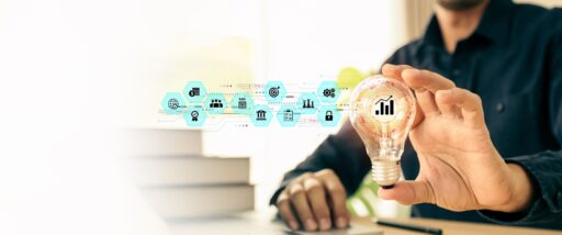 Hand wählt eine leuchtende Glühbirne mit Businessplan-Symbolen, daneben Bücher. Sinnbild für kreative Ideen, technologische Innovation, Wissensaufbau und finanzielle Bildung.